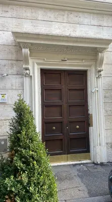 a large wooden door on a building with a bush at La casa di Nina in Via Veneto in Rome