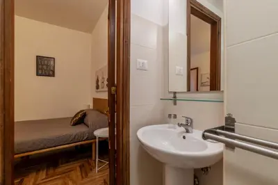 a bathroom with a sink and a mirror and a bed at GuestHost - Charming Apartment near Piazza di Spagna in Rome