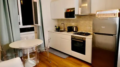 a small kitchen with a table and a refrigerator at La Nuova Casa Di Zia - near metro A Ponte Lungo in Rome