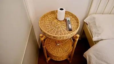 a wicker table with a remote control on it next to a bed at La Nuova Casa Di Zia - near metro A Ponte Lungo in Rome