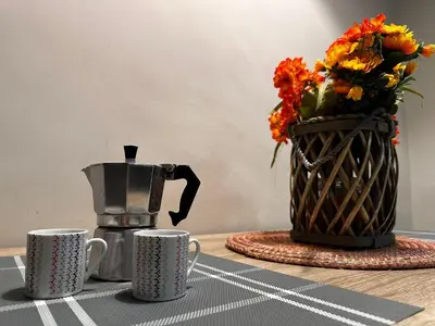 a table with two coffee cups and a vase of flowers at Trastevere Bertani MiniApartment in Rome