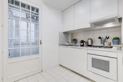 a white kitchen with a stove top oven next to a window at New opening Spagna Suite in Rome