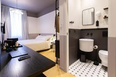 a hotel room with a bed and a desk and a bathroom at Saint Suites in Rome