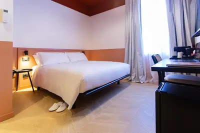 a hotel room with a bed and a desk and a window at Saint Suites in Rome