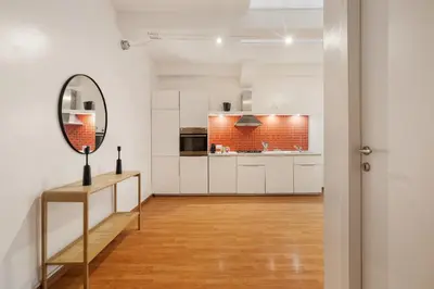 a kitchen with white cabinets and a mirror at Lungotevere Trastevere Loft in Rome