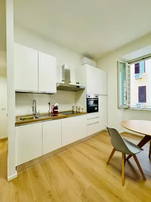 a kitchen with white cabinets and a table and a chair at Vaschome in Rome