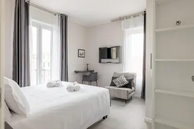 a white bedroom with a bed and a chair at Belli San Giovanni Guest House in Rome