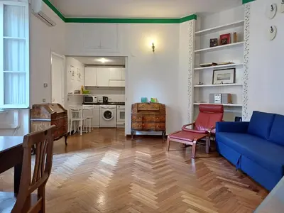 a living room with a blue couch and a kitchen at la casa del Duca a Monti in Rome
