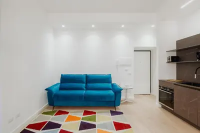 a blue couch in a living room with a kitchen at Giulio Cesare Flat - VATICAN in Rome