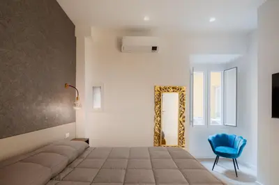 a bedroom with a bed and a blue chair and a mirror at Giulio Cesare Flat - VATICAN in Rome