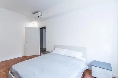 a bedroom with a white bed and a blue nightstand at Skylife Modern 4-Bedroom Trastevere Apartment in Rome