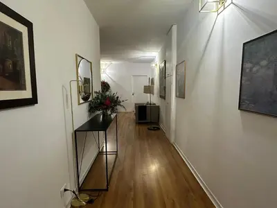 a hallway with white walls and wooden floors and paintings at RiversideMellini44 in Rome