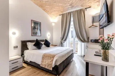 a bedroom with a bed and a desk with a television at Rose Inn Guest House in Rome
