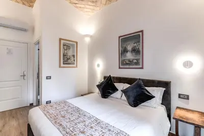 a bedroom with a white bed with black pillows at Rose Inn Guest House in Rome