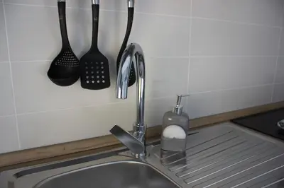 a kitchen sink with utensils hanging on a wall at Alicemaria Vatican Comfortable Apartment in Rome