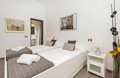 two beds in a room with white walls at Ungaretti Vatican Apartment in Rome