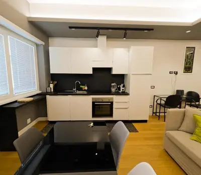 a kitchen and living room with white cabinets and a couch at Appartamento Appia metro A Colli Albani in Rome