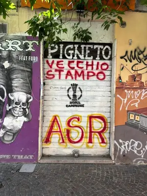 a garage door with graffiti on it with a sign at Roma, Città degli Uomini in Rome