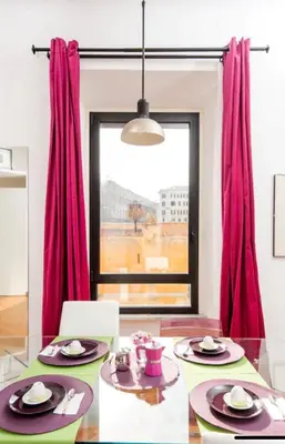 a dining room with a glass table and red curtains at LoL-ApartmenT, in the heart of Trastevere in Rome