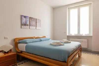 a bedroom with a bed with blue sheets and a window at Family Rooms in Rome