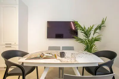 a white table with chairs and a tv on a wall at Residenza Gradinata al Vaticano in Rome
