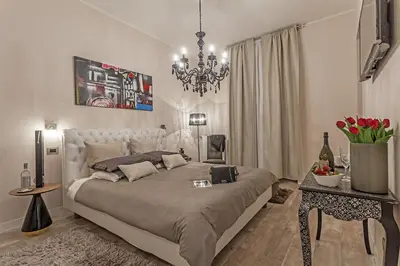 a white bedroom with a large bed and a chandelier at St. George's Vatican Suites in Rome