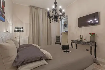 a bedroom with a bed and a table and a chandelier at St. George's Vatican Suites in Rome