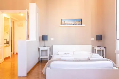 two beds in a white room with two tables at Amalia Vatican House in Rome
