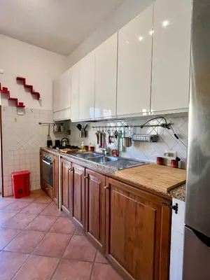 a kitchen with white cabinets and a wooden counter top at Domus Roma Apartment in Rome