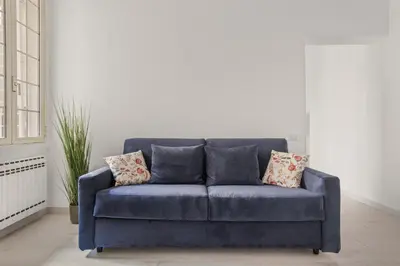 a blue couch with pillows in a living room at Visconti58 Boutique House - Modern apt with balcony in Rome