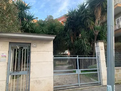 a gate in front of a building with palm trees at Peck House in Marconi San Paolo in Rome