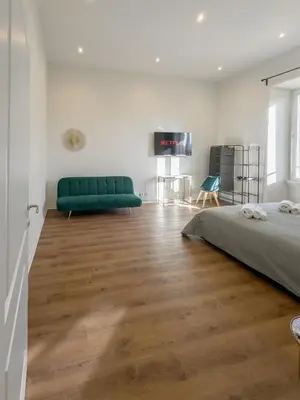 a bedroom with a green couch and a wooden floor at Colosseum Charme in Rome