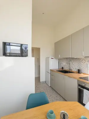 a kitchen with white cabinets and a wooden table at Colosseum Charme in Rome