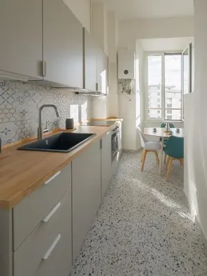 a kitchen with white cabinets and a sink and a table at Colosseum Charme in Rome