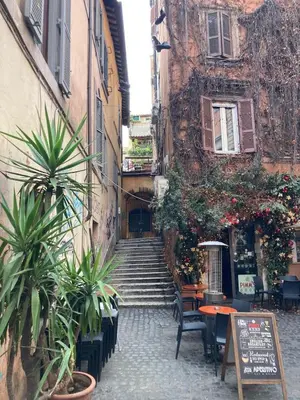 an alley with stairs and tables and potted plants at Trastevere Home Garibaldi 14 in Rome