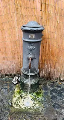 a water fountain with a face on it next to a wall at Trastevere Home Garibaldi 14 in Rome
