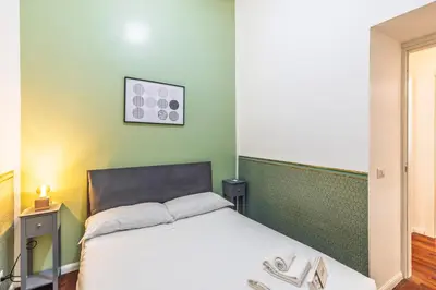 a bedroom with a white bed and a green wall at Domus Flavia Monti in Rome