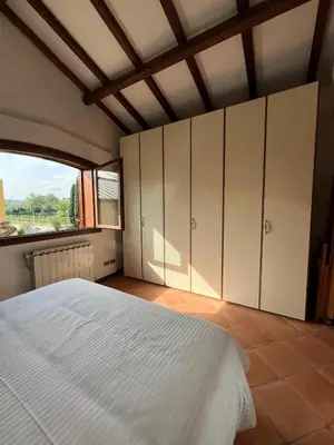 a bedroom with a white bed and a large window at Apartment in green oasis in Rome