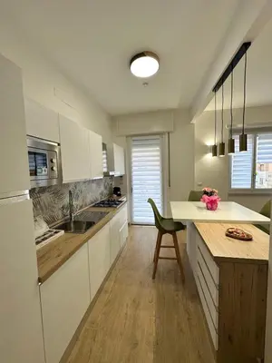 a kitchen with white cabinets and a green chair at Charming House Tuscolana - Roma in Rome