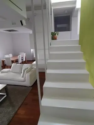 a white staircase in a living room with a white couch at La terrazza di Baccio - Baccio's Terrace in Rome