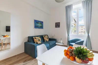 a living room with a blue couch and a table with a bowl of fruit at Hostly-The Porta Pia Suite-Rome Centre with Charme in Rome