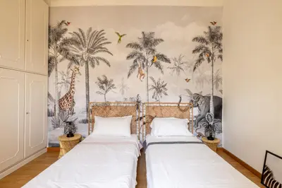 two beds in a bedroom with palm trees wallpaper at Elegant Penthouse with Terrace in Rome