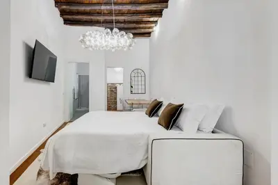 a bedroom with a large white bed and a chandelier at NEW ROMAN Apartment - Rome Dream Home in Rome