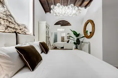 a bedroom with a large white bed and a chandelier at NEW ROMAN Apartment - Rome Dream Home in Rome