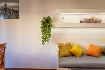 a couch with yellow pillows and a plant on a wall at Altavilla by Rental in Rome in Rome