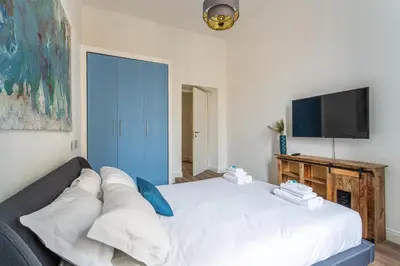 a bedroom with a white bed and a flat screen tv at iFlat Brand New & Modern Central Station apt in Rome