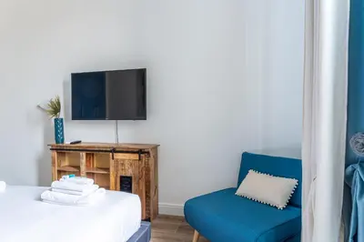 a bedroom with a bed and a blue chair at iFlat Brand New & Modern Central Station apt in Rome