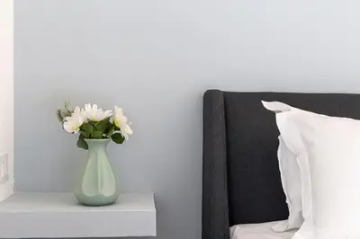 a vase with white flowers on a table next to a bed at iFlat Brand New & Modern Central Station apt in Rome
