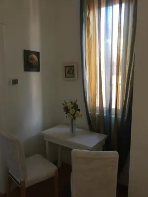 a table with a vase of flowers and two chairs at Angelo ai Musei Vaticani studio in Rome