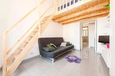 a living room with a black couch and stairs at Cozy House near Termini Station - San Lorenzo in Rome